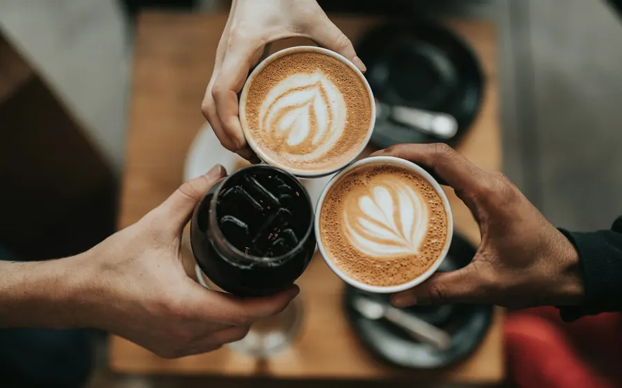 Two lattes held together over a wooden table