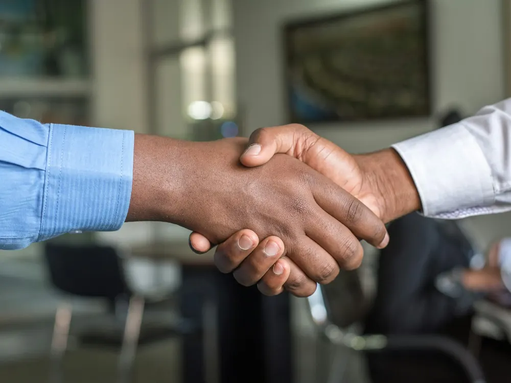 Two people shaking hands across a table